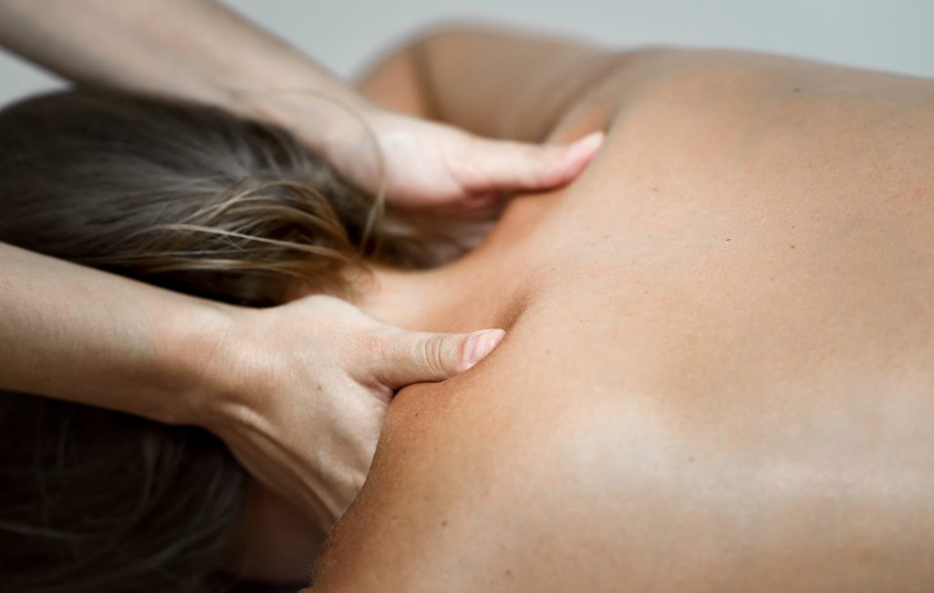 Young woman receiving a back massage in a spa center. Female patient is receiving treatment by professional therapist.
