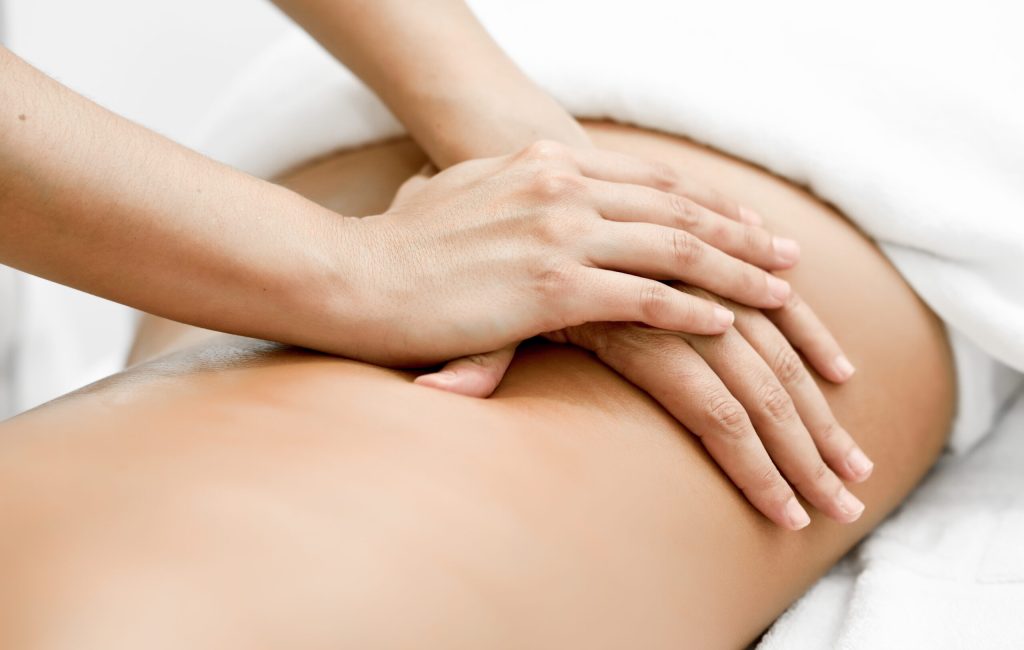 Young woman receiving a back massage in a spa center. Female patient is receiving treatment by professional therapist.